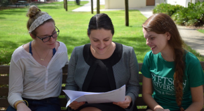 three women smiling and reading a document that danielle lindner (middle) is holding