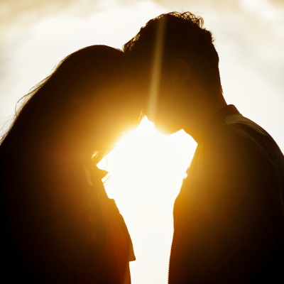 silhouette of a couple leaning toward each other with the sun in the background