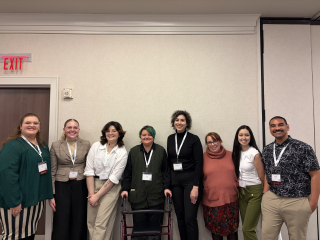eight students standing in a row at a conference