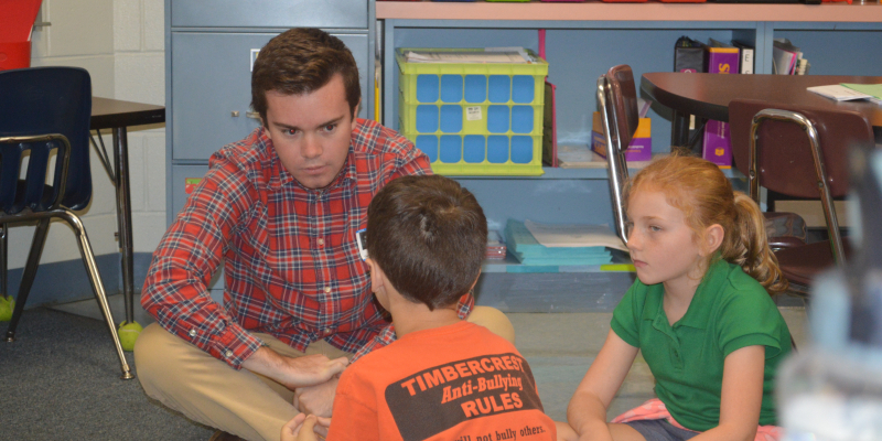 student working on project with kids at their school