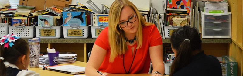 teacher working with two girls at school 