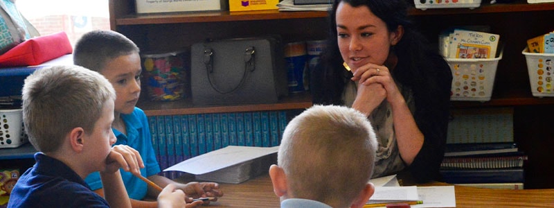 Teacher with three students talking on a classroom