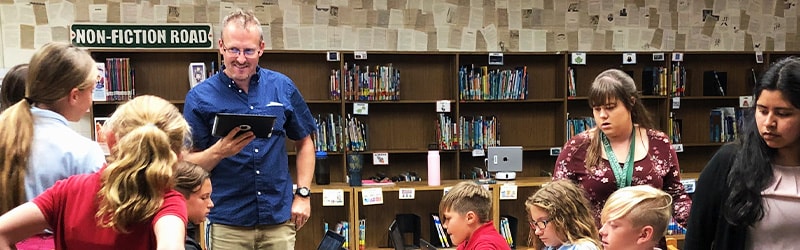 smiling teacher reading to students at schooll library 