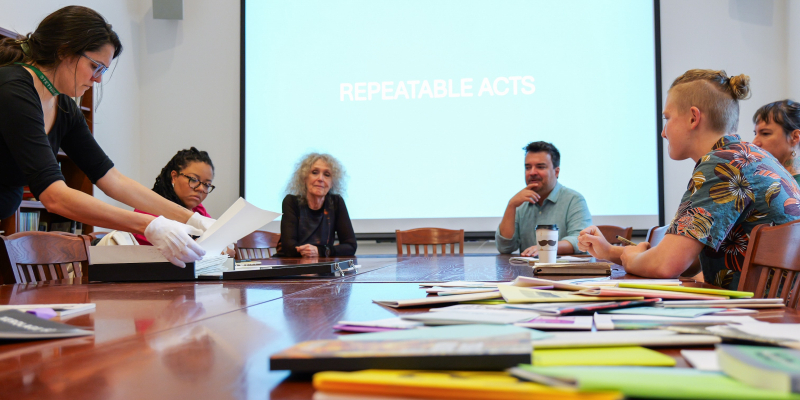 MFA students working together sitting down around table