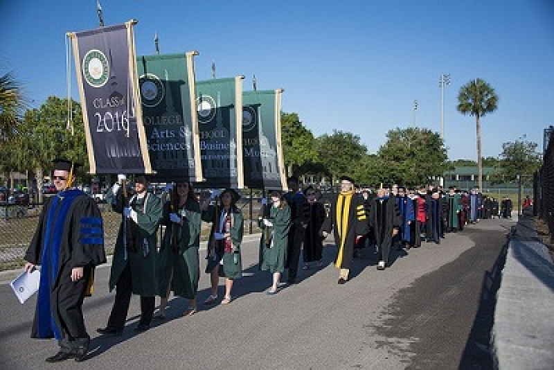 A procession of graduates and faculty in academic regalia