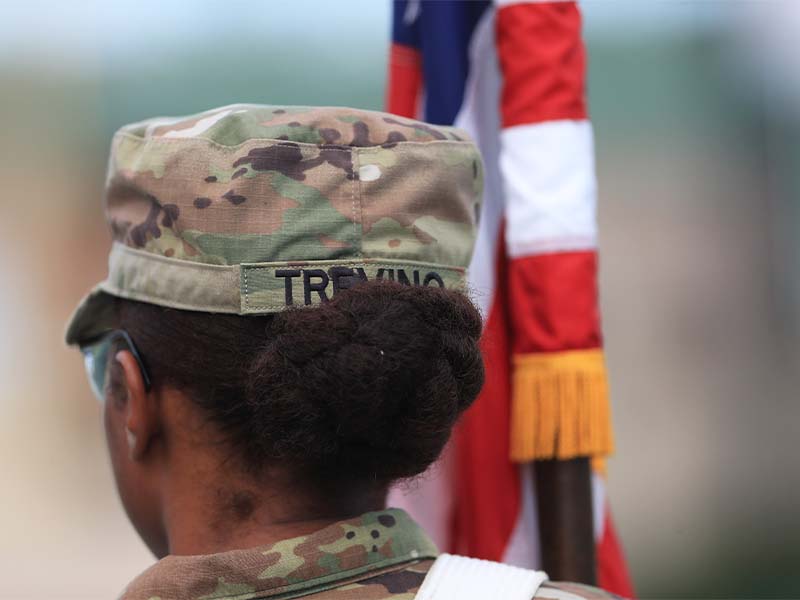 student in uniform next to american flag