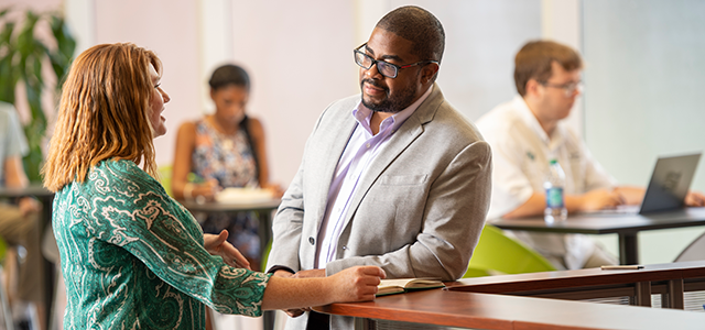 student speaking with faculty member