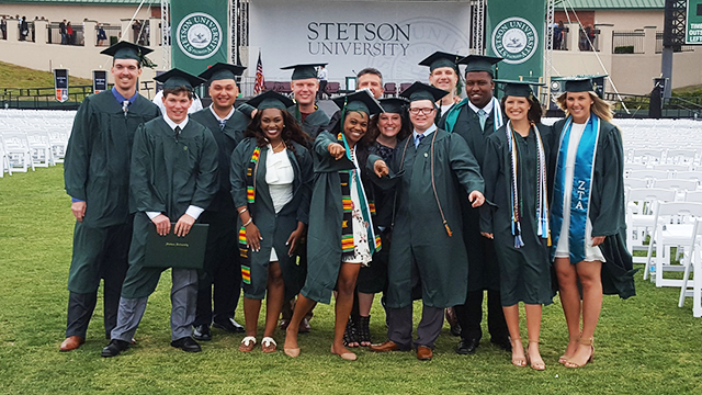 graduates pose for group photo in their academic regalia