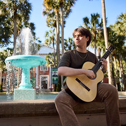 student playing guitar at the Holler Fountain
