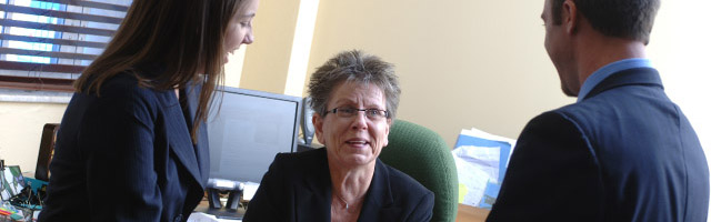 2 students speaking with professor in office