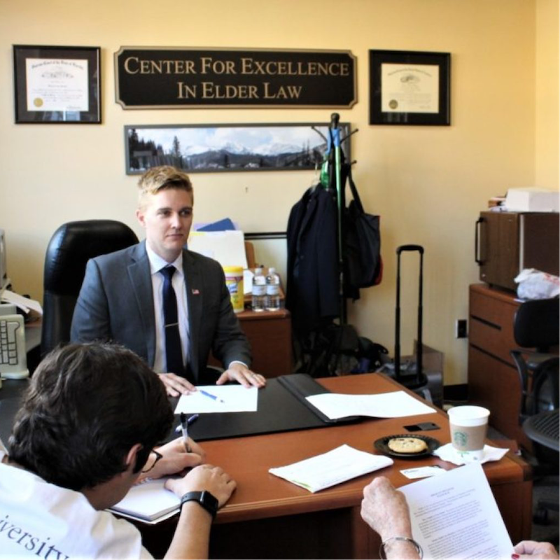 Three people sit inside the Elder Law office