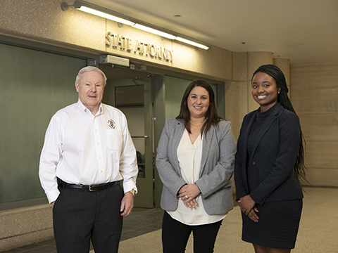 two students posing with a state attorney outside his office