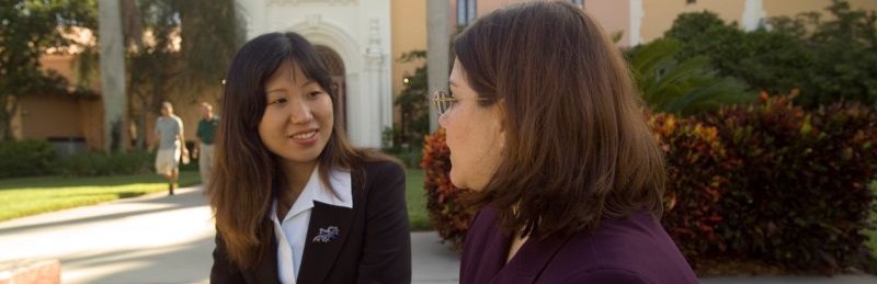 two women sitting and talking outside on campus