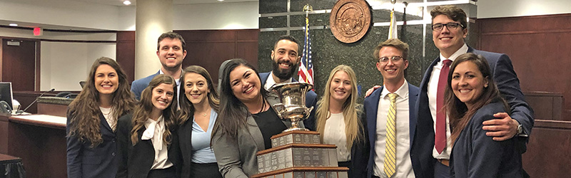 students surrounding a trophy