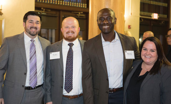 Four alumni taking a photo in suite jackets