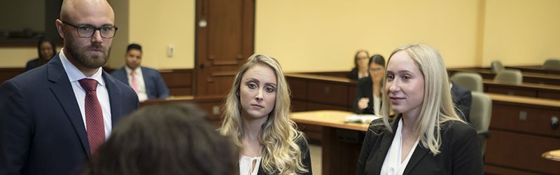 three students listening to a speaker
