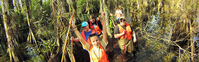 students and faculty hiking in swamp