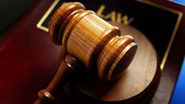 A wooden gavel laying on a law plaque