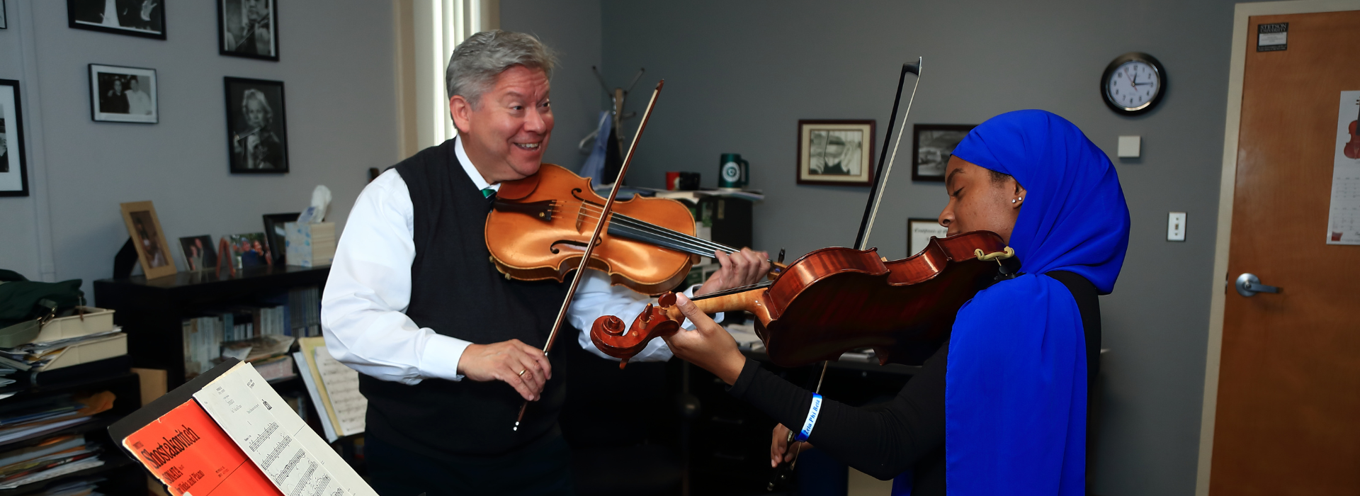 student and professor practing violin together