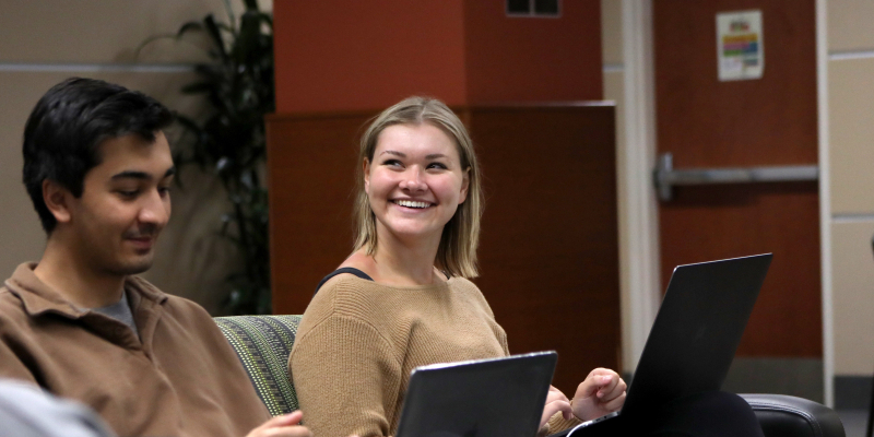 two students seating together looking over computer