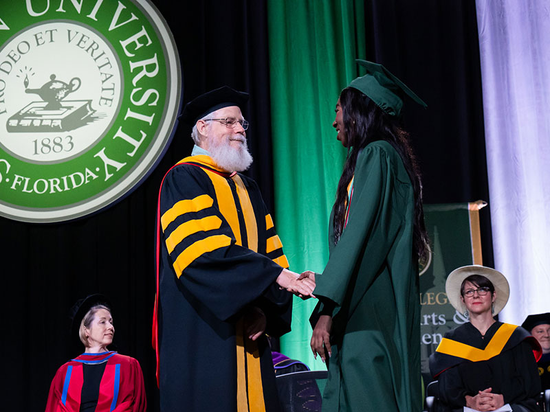 a student graduating on stage with a professor