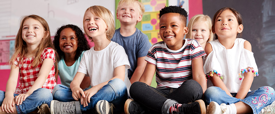 Happy young children sitting on the floor in their classroom