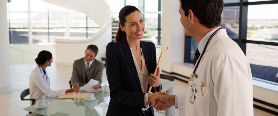 A doctor and nurse talking with people at a hospital.