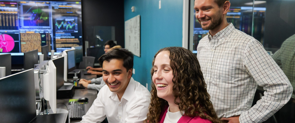 Students working on computers with RGIP-related data on a big screen in the background