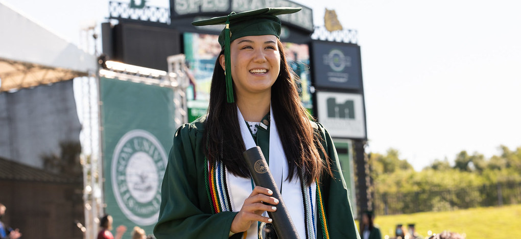 A graduating student smiling at the Commencement Ceremony.
