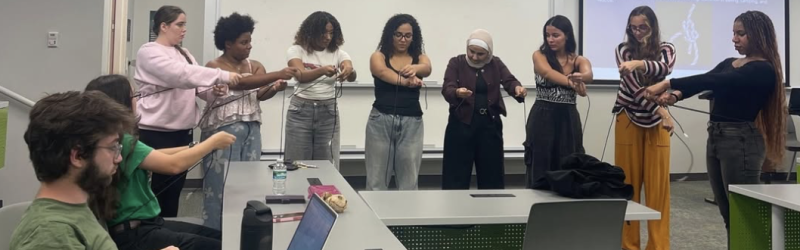 Students in a circle participating in a team boding activity with rope