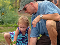 Adult helping a young girl digging