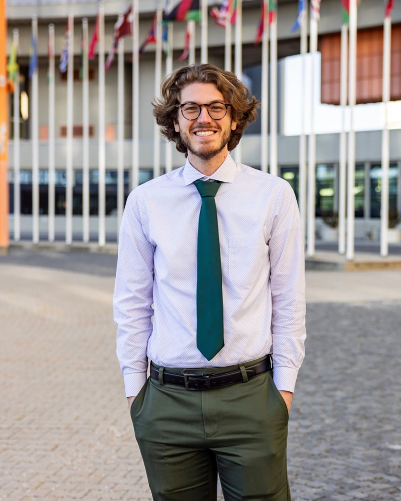 Jonah Helwig in front of building with flags