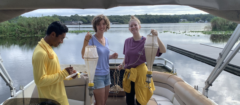 two students on boat holding up samples