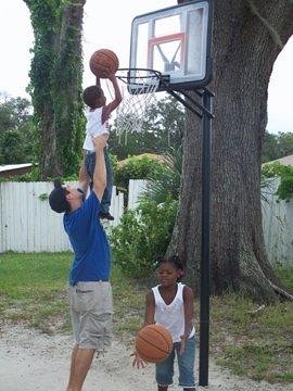 Student Helping Child Play Basketball