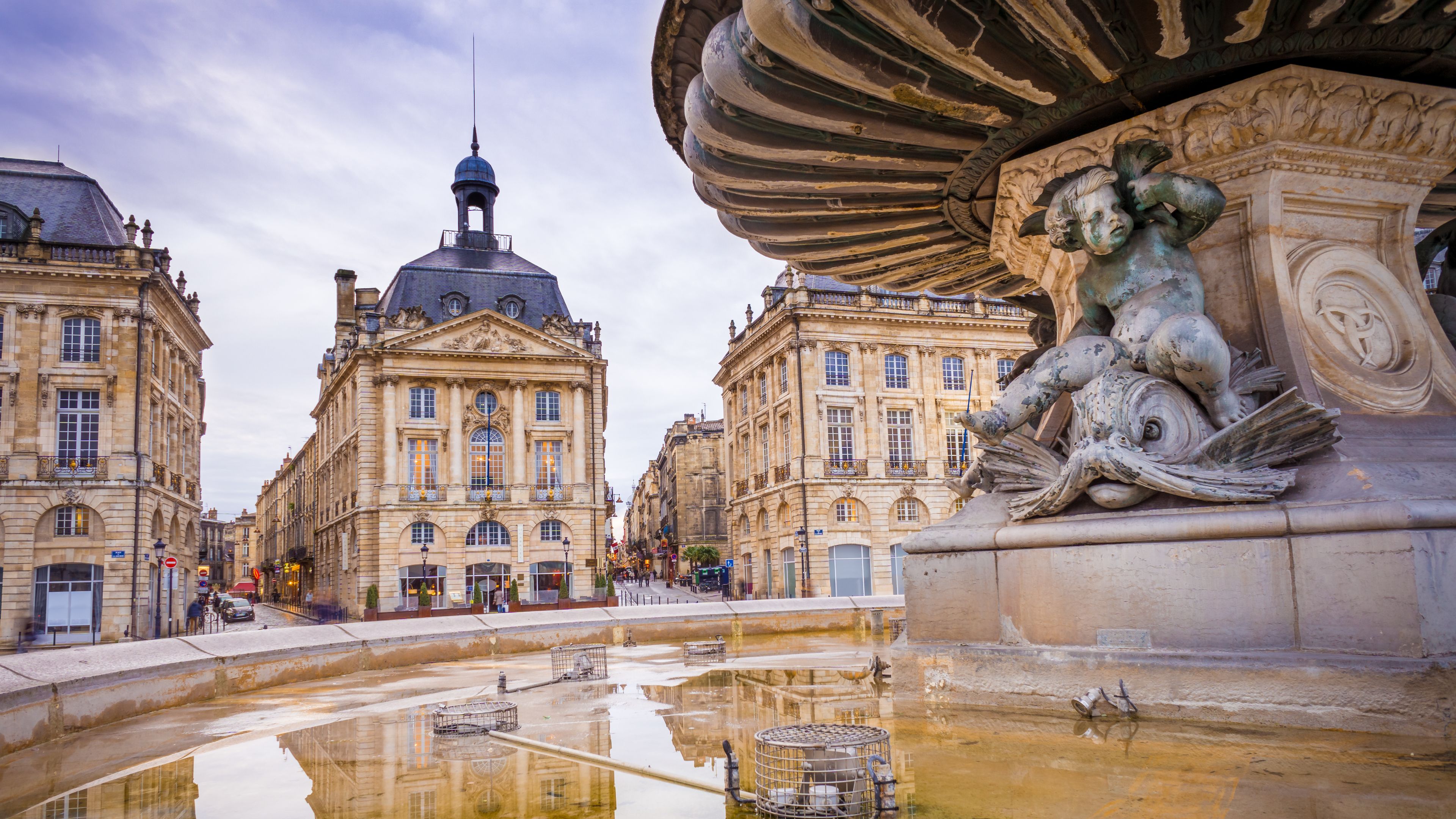 Reflections of Place de la Bourse buildings on the wet surface of the Miroir d'eau in Bordeaux, France