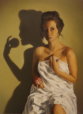 A woman sits holding a half-eaten apple.