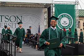 A graduate walks off stage with his diploma at the ceremony