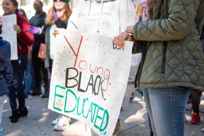 Participants hold a poster that says, "Young, Black, Educated."