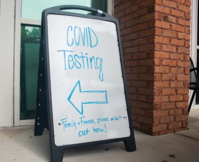A sandwich board sign says COVID-19 testing