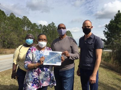 Four people post as two hold a map alongside State Road 92, west of Daytona