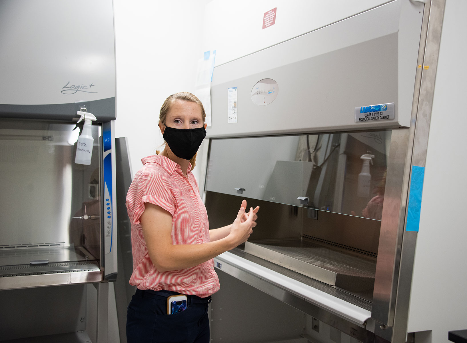 The professor stands in the new Sage Hall lab explaining how biosafety cabinets are used for experiments with viruses.