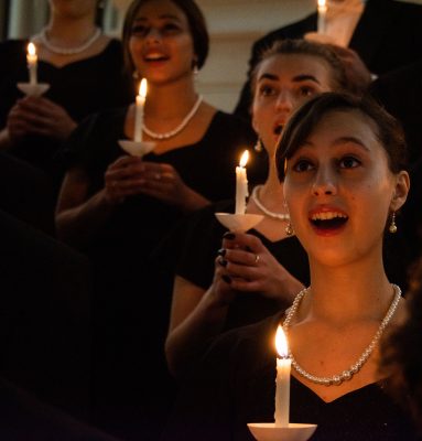 Choir members sing in the Christmas Candlelight concert, holding candels.
