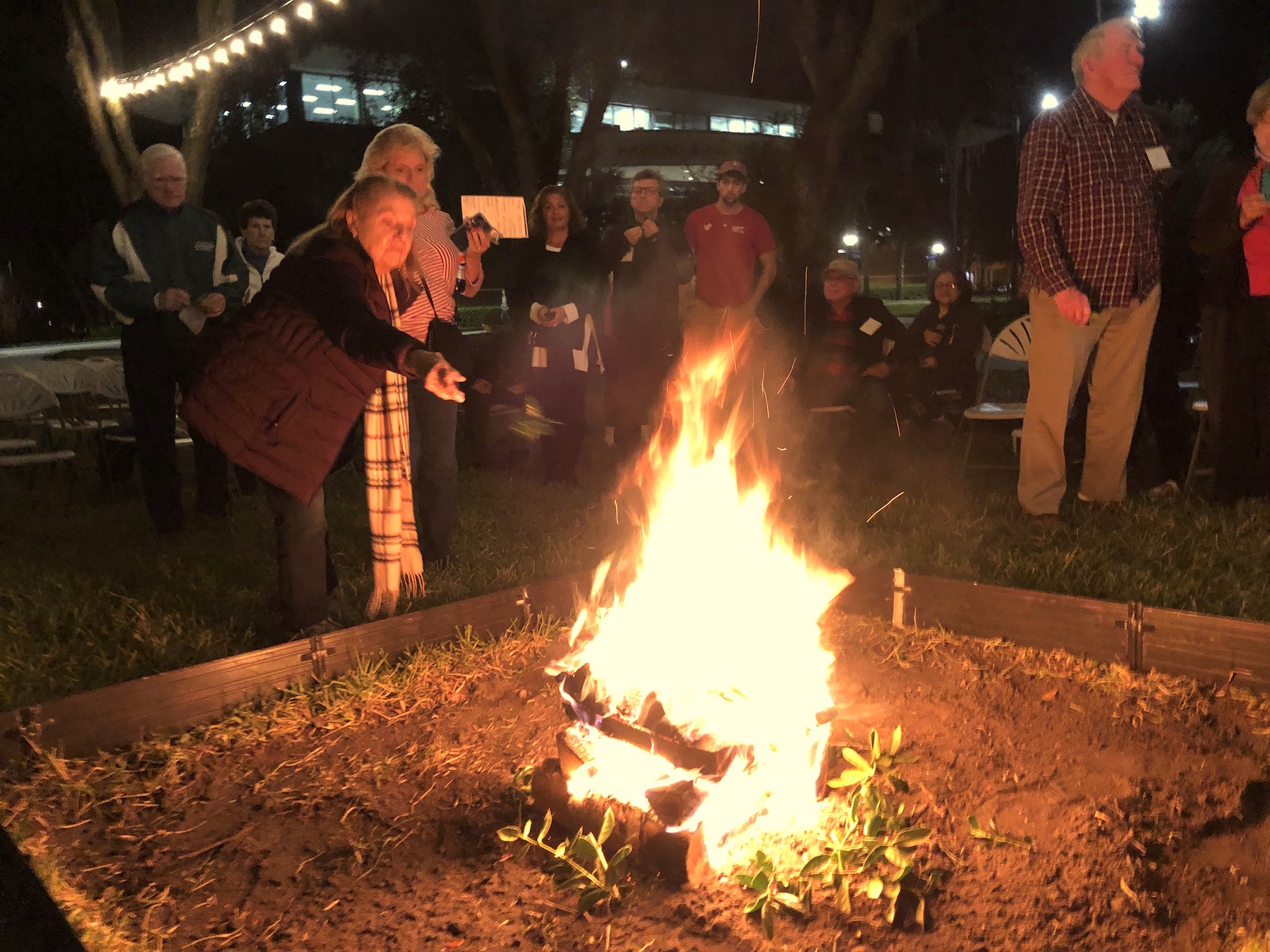People throw sprigs into the Yule Log bonfire